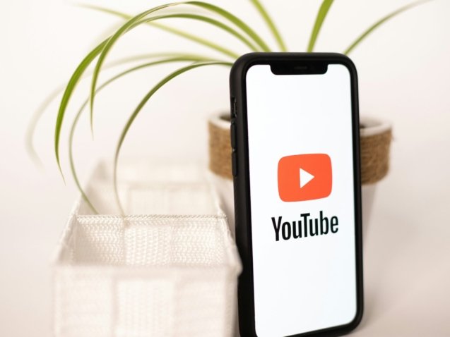 a phone with a youtube logo on it next to a potted plant