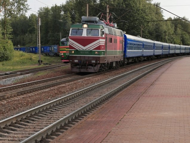 a train traveling down train tracks next to a forest