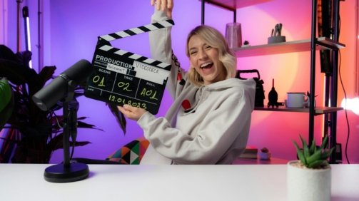 a woman holding a clapper in front of a camera