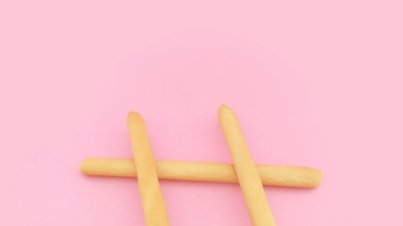 four brown wooden sticks on pink surface
