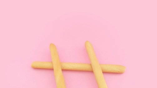 four brown wooden sticks on pink surface
