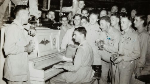 grayscale photo of 4 men standing beside piano