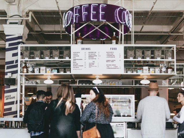 group of people standing in front of food stall counter
