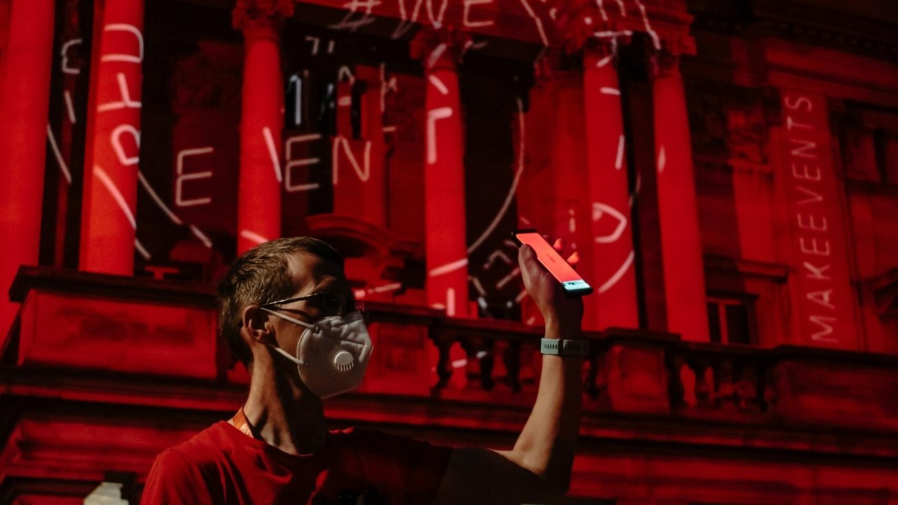 man in white crew neck t-shirt wearing black goggles standing near red building during nighttime