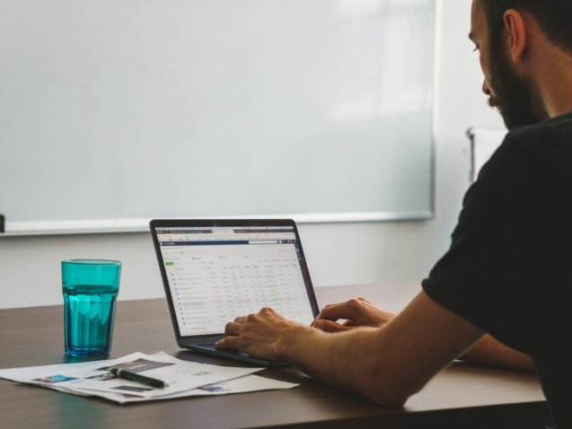man sitting at the table while using laptop computer