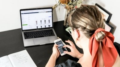 woman in orange shirt using iphone